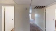 This single-floor unit is thoughtfully laid out to maximize functionality across its living spaces. The galley-style kitchen is well-appointed with rich, warm-toned wood cabinetry, granite-style countertops, and a full suite of black appliances including a refrigerator, electric range with microwave, and dishwasher. Wood-look vinyl flooring runs throughout the kitchen and extends to an adjacent laundry area, which houses an in-unit washer conveniently accessible via a sliding closet door. The carpeted bedrooms are generously proportioned, each featuring ceiling fans with light fixtures, textured ceilings, and vertical blind-covered windows that allow natural light to filter in. The hallways are carpeted and connect the living areas seamlessly, with a drop ceiling, HVAC vents, and smoke detectors noted overhead. Both bathrooms are finished consistently, featuring rich wood vanity cabinetry topped with granite-style countertops, wood-look flooring, large mirrors, and tub/shower combinations enclosed by sliding glass doors. The overall aesthetic is practical and cohesive, with neutral tones and consistent finishes throughout.