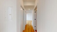 Located on the fifth floor of 619 North Broad Street in Philadelphia's vibrant Northern Liberties neighborhood, Unit 505 is a thoughtfully designed studio that maximizes every square foot with a clean, modern aesthetic. Light natural wood flooring runs throughout the entire unit, complementing the crisp white walls and recessed lighting to create a bright, airy feel.

The kitchen is a standout feature, showcasing a central island with a quartz countertop, an undermount sink with a gold-tone faucet, and warm terracotta-orange lower cabinetry paired with sleek white upper cabinets that extend to the ceiling for ample storage. A full suite of stainless steel appliances — including a French door refrigerator, electric range, over-the-range microwave, and a subtly patterned tile backsplash — gives the space a polished, contemporary finish.

The hallway connects the main living area to the bathroom and features a sliding closet door, recessed lighting, and clean white trim throughout. The open living area receives natural light through a large window with views of the surrounding cityscape.

The bathroom is a design highlight, featuring a tub-shower combination adorned with a striking gradient tile surround that transitions from white to yellow to vivid orange — a bold, artistic touch. Dark matte black fixtures, a rain showerhead, and mosaic floor tile complete the room's retro-modern character.