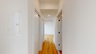 Located on the fifth floor of 619 North Broad Street in Philadelphia's vibrant Northern Liberties neighborhood, Unit 505 is a thoughtfully designed studio that maximizes every square foot with a clean, modern aesthetic. Light natural wood flooring runs throughout the entire unit, complementing the crisp white walls and recessed lighting to create a bright, airy feel.

The kitchen is a standout feature, showcasing a central island with a quartz countertop, an undermount sink with a gold-tone faucet, and warm terracotta-orange lower cabinetry paired with sleek white upper cabinets that extend to the ceiling for ample storage. A full suite of stainless steel appliances — including a French door refrigerator, electric range, over-the-range microwave, and a subtly patterned tile backsplash — gives the space a polished, contemporary finish.

The hallway connects the main living area to the bathroom and features a sliding closet door, recessed lighting, and clean white trim throughout. The open living area receives natural light through a large window with views of the surrounding cityscape.

The bathroom is a design highlight, featuring a tub-shower combination adorned with a striking gradient tile surround that transitions from white to yellow to vivid orange — a bold, artistic touch. Dark matte black fixtures, a rain showerhead, and mosaic floor tile complete the room's retro-modern character.