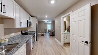 Located at 1551 Johnson Ferry Rd in Marietta, Georgia, this thoughtfully designed one-bedroom, one-bathroom unit makes excellent use of its compact footprint across a single floor. Light-toned luxury vinyl plank flooring runs throughout the main living areas, creating a clean, cohesive aesthetic complemented by warm neutral wall colors and crisp white trim.

The kitchen is well-appointed with white shaker-style cabinetry featuring black hardware, granite countertops, and a full suite of stainless steel appliances including a range, microwave, dishwasher, and refrigerator. A laundry area provides added in-unit convenience.

The open layout connects the kitchen to the living area, which offers comfortable space for lounging and features recessed and flush-mount lighting. A dedicated nook provides room for a desk or workspace, adding functional versatility.

The bedroom is carpeted for comfort and includes a closet with bifold doors. A sliding glass door opens directly to an outdoor patio with green space views, filling the room with natural light. The bathroom features white cabinetry with granite countertops and a walk-in shower with matte black fixtures. The overall ambiance is modern, clean, and move-in ready.