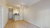 Located at 2350 Bagby St in Houston's Midtown neighborhood, this one-bedroom, one-bathroom unit offers a well-designed layout across a single floor. Light-toned hardwood-style flooring runs throughout the space, complementing the neutral warm-gray walls and crisp white trim and crown molding.

The combined living and dining area is open and airy, anchored by a set of French doors that flood the room with natural light and provide views of the surrounding greenery. A built-in shelving unit adds both function and character to the living space. Track lighting overhead ensures ample illumination throughout.

The kitchen features a breakfast bar peninsula with dark granite-style countertops, white cabinetry, and stainless steel appliances including a refrigerator, range, and microwave. The layout connects seamlessly to the living and dining area, making it ideal for everyday living.

The bedroom is a comfortable, well-proportioned room with a ceiling fan, a large window with outdoor views, and access to multiple closets. The bathroom is finished with white cabinetry, a dark countertop vanity, and clean, neutral tiling. A dedicated laundry area and hallway with additional closet storage round out the practical layout of this efficiently designed Houston residence.