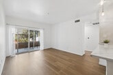 Located near the Hollywood Freeway in Los Angeles, this well-appointed 2-bedroom, 2-bathroom residence offers a bright, modern living environment across a single floor. Light-toned hardwood flooring runs throughout the space, creating a warm and cohesive aesthetic.

The kitchen is a functional highlight, featuring crisp white cabinetry with ample storage, a quartz countertop peninsula, stainless steel appliances including a range, microwave, and refrigerator, and pendant lighting that adds a contemporary touch. The kitchen opens directly to the living area, promoting an open-concept flow.

The living room is bathed in natural light thanks to large sliding glass doors that lead to a private balcony — ideal for outdoor dining or relaxing with greenery views. Both bedrooms are well-sized, with the primary bedroom offering a built-in sliding door closet and natural light from a dedicated window. The second bedroom is equally bright with sheer curtains framing its window.

The two bathrooms are finished in a clean, minimalist style. One features a glass-enclosed walk-in shower with tile finishes, a wide vanity, and wood flooring. The other includes a tiled shower-bath combination, a large mirror, and pendant lighting. A dedicated hallway and closet complete the thoughtful layout of this inviting Los Angeles residence.
