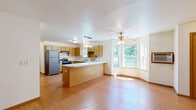 Located at 5730 Gatehouse Dr in Eau Claire, Wisconsin, this single-floor, three-bedroom, one-bathroom home offers a functional and cohesive layout throughout. The combined kitchen and living room serves as the heart of the home, featuring warm oak cabinetry, white countertops, a peninsula with pendant lighting overhead, and stainless steel appliances including a dishwasher and refrigerator. A ceiling fan with a light fixture anchors the living area, which is bathed in natural light from a large bay-style window offering pleasant views of the surrounding greenery. Hardwood flooring runs consistently throughout the entire home, lending warmth and continuity to every room. The three bedrooms are well-proportioned, with the primary bedroom featuring large windows that frame lush outdoor views and a ceiling fan. The additional bedrooms are bright with clean white walls and hardwood floors. The bathroom includes a walk-in shower with grab bar support, a wide vanity with oak cabinetry, and a large mirror with overhead lighting. A dedicated laundry room is equipped with washer and dryer hookups and overhead wire shelving for added storage. The home's straightforward, single-level design provides ease of navigation and practicality throughout.