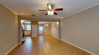 This three-floor home in Baton Rouge, Louisiana offers a well-designed layout across multiple levels, accommodating three bedrooms and three and a half bathrooms. The main level features an open living and dining area finished with large neutral-toned ceramic tile flooring, crown molding, and ceiling fans that add both style and comfort. A carpeted staircase with white railings connects the floors, and natural light filters in through multiple windows near the entry.

The kitchen is thoughtfully appointed with white raised-panel cabinetry, tile countertops, a double-basin sink, black appliances including an electric range and dishwasher, and pendant lighting overhead. A pass-through counter extends into the dining area, creating an open, connected feel.

Upper levels feature rich hardwood flooring throughout the bedrooms. One room includes French doors that open to bring in additional natural light, while another bedroom benefits from crown molding and direct access to an en-suite bathroom with dark wood cabinetry and a granite-topped vanity. The half bath on another level mirrors this refined aesthetic with an ornate dark wood vanity and dark stone countertop. Hallways connect the bedrooms with tile flooring and clean white trim, completing a cohesive and functional living environment.