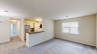 Located at 26 Cheswold Blvd in Newark, Delaware, this single-floor residence offers a practical and well-organized layout designed for comfortable everyday living. The open-concept living area is anchored by soft, wall-to-wall carpeting and warm neutral-toned walls that create a bright, welcoming atmosphere. A window with slatted blinds allows natural light to filter in, enhancing the sense of openness throughout the space.

The kitchen is positioned adjacent to the living area and separated by a peninsula counter with a dark laminate surface, offering a natural divide while maintaining visual connectivity. Inside, the kitchen features light wood-toned cabinetry, hardwood-style flooring, dark countertops, and stainless steel appliances including a refrigerator, built-in microwave, and electric range.

The bedrooms are carpeted and finished with the same neutral palette, each benefiting from natural light through windows with blinds. One bedroom includes a spacious walk-in closet, while another offers a standard closet with room to spare. The bathroom is cleanly appointed with tile flooring, a vanity with storage, a tiled shower surround, and grab bar accessibility features. Overall, the residence presents a clean, functional, and move-in ready environment.