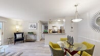 Located at 67 Village Lane in Wethersfield, Connecticut, this single-floor residence offers a thoughtfully designed layout with a bright, open-concept living and dining area at its core. Light-toned hardwood-style flooring flows throughout the main living spaces, contributing to a cohesive and airy aesthetic. Neutral wall tones and smooth ceilings enhance the sense of openness throughout.

The living room is generously proportioned and anchored by a sliding glass door that leads to a private balcony, allowing natural light to fill the space and providing pleasant outdoor views. The kitchen is positioned adjacent to the living and dining areas, separated by a peninsula counter finished with granite-style countertops. White cabinetry and stainless steel appliances, including a refrigerator and electric range, give the kitchen a clean, modern character. A dedicated dining area with a pendant light fixture sits nearby, offering a defined space for meals.

The bedroom is a comfortable retreat featuring plush carpeting, a large window that admits natural light, and direct access to a well-appointed bathroom. The bathroom features a white vanity with ample storage, a wide mirror with overhead lighting, and hardwood-style flooring that maintains continuity with the rest of the home. The overall ambiance throughout is calm, contemporary, and move-in ready.