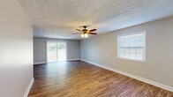 This two-floor residence in Lexington, Kentucky offers three bedrooms and two bathrooms within a well-organized layout designed for comfortable everyday living. Wood-style flooring runs consistently throughout the home, providing a warm, cohesive aesthetic that complements the neutral, light gray wall tones found in each room.

The living area is notably spacious, featuring a ceiling fan with light fixture, a sliding glass door that invites abundant natural light, and an additional side window that further brightens the space. The open sightlines between the living area and kitchen create a connected, practical flow. The kitchen is equipped with white shaker-style cabinetry, granite-look countertops, a subway tile backsplash, a stainless steel sink, and a stainless steel refrigerator, all complemented by a window overlooking the outdoors.

Each bedroom is well-proportioned, featuring windows that bring in natural light and textured ceilings consistent throughout the home. The bedrooms offer clean, neutral finishes with white panel doors and ample wall space. The bathrooms maintain the home's understated, functional design with brushed nickel hardware accents. Overall, the space presents a clean, updated interior with consistent finishes and a bright, welcoming atmosphere across both floors.