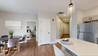 Located at 898 Buffalo Rd in Gates Center, NY, this thoughtfully designed single-floor residence combines modern aesthetics with functional living. Rich hardwood-style flooring runs throughout, providing a warm, cohesive foundation across every room.

The open-concept kitchen is a standout feature, outfitted with shaker-style gray cabinetry, crisp white countertops, stainless steel appliances, and a large center island with seating for multiple guests. Mason jar pendant lights add a stylish, contemporary touch above the island. A sliding glass door in the adjacent living and dining area allows natural light to pour in while offering direct outdoor access and neighborhood views.

The living room features corner windows with white plantation blinds, creating a bright, airy atmosphere ideal for relaxing or entertaining. A dedicated office space provides a quiet retreat with its own window for natural light, suitable for professional or personal use.

The bedroom is generously sized with a large window, neutral tones, and ample closet access via paneled white doors. The bathroom is finished with a shaker-style vanity, matte black fixtures, a large mirror, and industrial-style lighting. A wide, well-lit hallway connects the various rooms with ease, reinforcing the home's clean, organized layout. The overall design strikes a balance between comfort, style, and practicality.