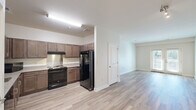 Located at 400 Katrina Court in Midlothian, VA, this single-floor, 3-bedroom, 2-bathroom home offers a well-organized layout with a clean, modern aesthetic. The kitchen is a functional centerpiece, featuring rich medium-toned wood cabinetry, light granite-style countertops, a stainless backsplash, and black Whirlpool appliances including a range and French door refrigerator. It opens directly into the living area, which is finished with light wood-style flooring that extends throughout the main living spaces. The living room is bright and airy, highlighted by French doors that provide natural light and access to an outdoor balcony area. Three bedrooms offer comfortable, carpeted retreats, each with double-panel closet doors and neutral wall tones. The primary bedroom includes a spacious double closet. Two bathrooms serve the home: one features wood-look tile flooring and a walk-in shower area, while the other includes a full soaking tub with white subway tile surround. A hallway connects the bedrooms to the main living areas, maintaining a practical and efficient flow throughout the home. The overall ambiance is clean, neutral, and move-in ready.