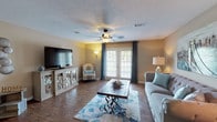 Located at 6721 Washington Ave in Ocean Springs, Mississippi, this single-story residence offers a thoughtfully designed layout across multiple living spaces. The living room serves as the heart of the home, showcasing rich wood-style flooring, a textured ceiling, and a ceiling fan with light fixture. French doors flood the space with natural light and provide outdoor access, while warm, neutral wall tones create an inviting atmosphere throughout.

The kitchen is equipped with dark espresso cabinetry extending to the ceiling for ample storage, stainless steel appliances including a French door refrigerator, gas range, and built-in microwave. A granite-topped breakfast bar provides casual dining space and opens the kitchen to the adjoining areas.

The bedrooms are carpeted and comfortably sized, each featuring ceiling fans or warm ambient lighting. The primary bedroom offers a retreat-like feel with a generous layout. A flexible room serves well as a home office or additional sleeping space, complete with carpet flooring, a closet, and a window with decorative curtains.

The bathrooms feature dark wood vanities topped with granite countertops, wood-style flooring, and well-lit mirrors. The primary bath includes a double-sink vanity and a bathtub, while a secondary bath provides a single-sink vanity. The overall aesthetic throughout the home is cohesive, warm, and move-in ready.
