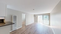 Located at 9128 Burke St in Pico Rivera, CA, this single-floor unit offers a clean, modern aesthetic throughout. Light wood-style flooring flows seamlessly across all living areas, complemented by neutral greige walls and crisp white trim that create a bright, cohesive atmosphere.

The open living area is generously sized, featuring a sliding glass door that floods the room with natural light and provides access to an outdoor balcony or patio. A wall-mounted AC unit ensures year-round comfort, while a built-in wall heater adds additional climate control. The layout connects smoothly to adjacent rooms, allowing for a natural flow through the space.

The kitchen is well-appointed with white shaker-style cabinetry, dark countertops, and stainless steel appliances including a refrigerator, range, and microwave. The bedroom areas are comfortably sized, each with windows fitted with blinds for light control and privacy. One bedroom also features a closet accessible via a hallway.

The bathrooms are tastefully updated, featuring white subway tile tub-shower combinations, modern chrome fixtures, and a vanity with a dark countertop, undermount sink, and contemporary lighting above a large mirror. Light wood flooring continues throughout the bathrooms, tying the space together with a consistent, polished finish.