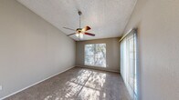 Located at 5320 Thunder Creek Rd in Austin, TX, this single-story, 2-bedroom, 1-bathroom home offers a functional and comfortable layout. The living area features plush carpet flooring, a ceiling fan, and a sliding glass door flanked by vertical blinds that invite natural light and provide outdoor access. The spacious primary bedroom boasts vaulted ceilings, a ceiling fan with light fixture, wide windows with tree-lined views, and a sliding mirror closet door for ample storage. The second bedroom is comparably sized, also carpeted, and benefits from a window that brings in natural light, connecting seamlessly to the rest of the home. The galley-style kitchen is efficiently designed, featuring warm wood cabinetry, laminate countertops, a stainless steel sink, wood-look vinyl flooring, and white appliances including a range, oven, refrigerator, and dishwasher. The bathroom includes a full tub and shower combo with clean white tile surround and wood vanity cabinetry. Textured ceilings are consistent throughout, and neutral warm-gray wall tones create a cohesive, understated aesthetic. This home offers practical living in a well-established Austin neighborhood.