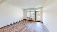 Located at 5317 Palouse Hwy in Spokane, WA, this one-bedroom, one-bathroom unit offers a thoughtfully laid-out single-floor plan with a comfortable and functional living environment. The open living room features warm wood-style flooring, a textured ceiling, baseboard heating, and large windows paired with a glass door that invite natural light and offer pleasant outdoor views of surrounding greenery. The galley-style kitchen is well-appointed with rich oak cabinetry both above and below the counters, white appliances including a range, microwave, refrigerator, and dishwasher, and a double-basin sink with ample counter space. A convenient pass-through connects the kitchen to the living area, enhancing the open feel of the shared space. The carpeted bedroom provides a cozy retreat with a window framing a tree-lined view and baseboard heating for year-round comfort. The full bathroom includes warm oak vanity cabinetry, a wide white countertop, a large mirror with Hollywood-style lighting above, and a shower-tub combination. A dedicated closet adds practical storage, and the unit also includes an accessible electrical panel. The consistent use of warm wood tones and neutral walls throughout creates a cohesive, welcoming ambiance.