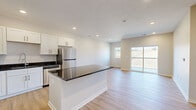 Located at 2209 First Ave in Plattsmouth, Nebraska, this well-appointed one-bedroom, one-bathroom unit offers a thoughtfully designed open-concept layout. Light wood-look flooring runs throughout the main living areas, creating a bright and cohesive feel. The kitchen is a standout feature, equipped with crisp white shaker cabinetry, dark granite countertops, stainless steel appliances including a refrigerator, range, microwave, and dishwasher, and a central island that provides additional prep and seating space. Recessed lighting illuminates the kitchen and living area, which flows seamlessly toward a sliding glass door opening onto a private balcony overlooking open, natural surroundings. The living room benefits from abundant natural light through the balcony door and an additional window framing the outdoor views. The bedroom is generously sized, finished with plush carpet, a ceiling fan, and a window with outdoor views, and connects directly to a dedicated walk-in closet with built-in shelving. The bathroom features a full tub-shower combo, white cabinetry, dark granite countertops, and wood-look flooring, maintaining the consistent, modern aesthetic found throughout the unit.