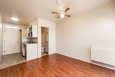 This single-floor studio is thoughtfully laid out to maximize functionality and comfort. The main living area is finished with rich hardwood flooring that runs throughout, lending warmth and a clean, polished aesthetic to the space. A ceiling fan overhead provides year-round comfort, while neutral-toned walls keep the interior feeling bright and open.

A sliding glass door connects the living area to a private balcony enclosed by a modern perforated metal railing. The balcony offers open views of the surrounding urban neighborhood, with palm trees and city rooftops visible against a bright sky — a characteristic touch of the Southern California setting.

The kitchen area features granite-look countertops, built-in cabinetry with a microwave, and a compact sink, providing all the essentials in an efficient footprint. A pass-through layout connects the kitchen seamlessly to the main living space.

The bathroom is clean and well-appointed, featuring a combined tub and shower, a toilet, a vanity with sink, and a large mirror that enhances the sense of space. A separate open closet area adjacent to the bathroom offers convenient storage.

Natural light filters in generously through the balcony door and a transom window, keeping the interior feeling airy throughout the day. The overall design is practical and move-in ready, suited for comfortable urban living.