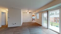 This single-floor unit offers a practical and well-organized layout across several distinct spaces. The main living area is generously sized, featuring warm neutral carpet, white walls, and a ceiling fan with integrated lighting. A sliding glass door fills the room with natural light and provides direct access to an outdoor area, offering views of the surrounding greenery. A second carpeted room, also equipped with a ceiling fan, includes a closet and serves well as a bedroom, with a window that invites additional natural light.

The kitchen is efficiently designed with warm oak cabinetry, granite-style countertops, and light tile flooring. It is fully equipped with white appliances, including a gas range, over-the-range microwave, dishwasher, and refrigerator. A stacked washer and dryer unit is conveniently located within the kitchen area, adding in-unit laundry functionality.

The unit includes two bathrooms. One features a full soaking tub with a surrounding shower enclosure and tile flooring, while the second offers a standalone shower stall with built-in shelving, tile flooring, and a vanity. Both bathrooms are clean and bright with a simple, functional aesthetic throughout.