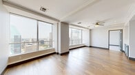 Located in the heart of Dallas, TX, this high-rise residence offers two bedrooms, three bathrooms, and a thoughtfully designed single-floor layout. Floor-to-ceiling windows are a defining architectural feature throughout, flooding the living spaces with natural light and framing breathtaking panoramic views of the Dallas skyline, including iconic landmarks such as Fountain Place.

The open-concept living and kitchen area is anchored by wide-plank hardwood flooring and a striking kitchen featuring slate-blue cabinetry, glass-front upper cabinets, a white quartz waterfall island, a mosaic tile backsplash, and stainless steel appliances. A dedicated hallway with built-in cabinetry topped with quartz countertops provides additional storage and connects the main living area to the private quarters.

Both bedrooms are carpeted and equipped with ceiling fans, benefiting from expansive city views through large windows. The spacious primary bedroom includes a generous walk-in closet with built-in shelving and dark wood cabinetry with brass hardware. The bathrooms are finished with tile flooring, and one features a glass-enclosed walk-in shower with floor-to-ceiling stone-effect tile and hexagonal mosaic floor tiles. A separate water closet with overhead cabinetry adds functional privacy.