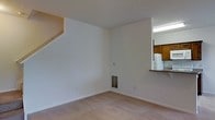 Located at 1 Village Gate Blvd in Delaware, Ohio, this two-story residence offers a practical and functional layout designed for comfortable everyday living. The main level features a spacious living area finished with neutral-toned carpeting and clean white walls that lend a bright, open feel to the space. A staircase leads to the upper floor, adding a sense of vertical dimension to the home. A pass-through opening connects the living area directly to the kitchen, promoting an open and communicative flow between the two spaces. The kitchen is outfitted with warm wood-toned cabinetry, a white refrigerator, and a dark countertop surface visible through the pass-through, giving it a classic and functional character. A floor vent provides climate control to the main living space, and the textured ceiling adds a subtle architectural detail throughout. The second floor expands the living footprint further, offering additional private space above the main level. Overall, the residence presents a straightforward and welcoming interior, well-suited for those seeking a clean, move-in ready home in the Delaware, Ohio area.