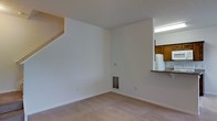 Located at 1 Village Gate Blvd in Delaware, Ohio, this two-story residence offers a practical and functional layout designed for comfortable everyday living. The main level features a spacious living area finished with neutral-toned carpeting and clean white walls that lend a bright, open feel to the space. A staircase leads to the upper floor, adding a sense of vertical dimension to the home. A pass-through opening connects the living area directly to the kitchen, promoting an open and communicative flow between the two spaces. The kitchen is outfitted with warm wood-toned cabinetry, a white refrigerator, and a dark countertop surface visible through the pass-through, giving it a classic and functional character. A floor vent provides climate control to the main living space, and the textured ceiling adds a subtle architectural detail throughout. The second floor expands the living footprint further, offering additional private space above the main level. Overall, the residence presents a straightforward and welcoming interior, well-suited for those seeking a clean, move-in ready home in the Delaware, Ohio area.