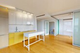 Located in Vancouver's West End (V6G), this well-appointed 2-bedroom, 2-bathroom apartment offers a thoughtfully designed single-level layout. Warm hardwood flooring flows throughout the main living areas, complementing a clean, modern aesthetic defined by white walls and abundant natural light.

The open-concept kitchen features glossy white upper cabinetry, bold yellow lower cabinets, a stainless steel sink, and track lighting overhead. A freestanding white island provides additional workspace and anchors the kitchen-living zone. Frosted glass sliding doors add a refined architectural touch, separating spaces while maintaining an airy feel.

Both bedrooms are bright and well-proportioned, each benefiting from large floor-to-ceiling windows that frame sweeping views of the Vancouver skyline and glimpses of the water beyond. The primary bedroom includes a spacious sliding-door closet with integrated shelving. A second closet offers further storage convenience.

The bathrooms are finished to a high standard, with one featuring marble-look tile flooring, a frameless glass walk-in shower with a rain showerhead, and a wall-mounted vanity. In-suite laundry and a private balcony round out the functional amenities. This apartment delivers a bright, contemporary urban living experience in one of Vancouver's most vibrant neighborhoods.