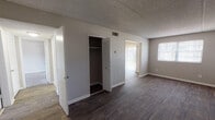 This single-floor residential unit offers a well-organized layout across several functional living spaces. The main living area features dark hardwood-style flooring paired with a textured ceiling and a vertical shiplap accent wall, creating a clean and modern aesthetic. Natural light filters in through windows fitted with blinds, brightening the open space. A dedicated closet with louvered bifold doors provides convenient storage directly off the living area.

The kitchen is efficiently designed with ample white raised-panel cabinetry extending to the ceiling, light-toned countertops, a stainless sink, and black appliances including a range and refrigerator. Light tile flooring completes the space.

The bedrooms are carpeted for comfort and feature neutral gray walls, textured ceilings, and louvered closet doors. One bedroom includes access to an adjacent walk-in shelving area, while another connects directly to a bathroom — offering added privacy and convenience.

Two bathrooms serve the unit: one features a glass-enclosed shower stall with built-in shelving and a single-sink vanity with white cabinetry, while the second includes a full tub-shower combo with tile surround and a matching vanity. Both bathrooms are finished with light tile flooring and textured walls, maintaining a cohesive, clean look throughout.