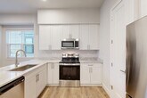 Located at 1773 Hideaway Lane Dr in Ann Arbor, MI, this modern four-bedroom, four-bathroom home spans four floors with a thoughtfully designed layout. Light wood-look flooring flows consistently throughout, complemented by neutral gray-toned walls and crisp white trim that lend a clean, contemporary feel to every room.

The kitchen is a standout feature, showcasing white shaker-style cabinetry extending to the ceiling, marble-look countertops, stainless steel appliances including a GE range, microwave, and refrigerator, and a peninsula ideal for casual dining. A dedicated pantry adds convenient storage. The adjacent combined dining and living area is bright, with large windows drawing in natural light.

The four bedrooms are generously proportioned, each with light wood flooring, neutral walls, and ample closet space with sliding doors. The primary bedroom offers a comfortable retreat with a well-sized layout. The four bathrooms feature white cabinetry, stone-look countertops, wood-look flooring, and clean tub-shower combinations.

Additional highlights include two laundry areas, a den, an attached garage with an automatic opener, and an unfinished basement offering excellent storage or finishing potential. Multiple staircases connect the four levels efficiently, rounding out this well-appointed Ann Arbor home.