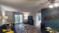 Located at 2 Riceville Rd in Asheville, NC, this single-floor residence offers a well-designed layout that balances comfort and functionality. The open-concept living and dining area is finished with wood-style plank flooring throughout, neutral-toned walls accented by a bold teal feature wall, and a textured ceiling. A ceiling fan with integrated lighting serves the dining area, while a sliding glass door floods the living space with natural light and provides direct access to a private outdoor patio with wooded views.

The kitchen features white cabinetry, granite-style countertops, a teal tile backsplash, and white appliances including an electric range and refrigerator. An adjacent pantry with built-in shelving adds practical storage.

The unit includes two carpeted bedrooms, each benefiting from natural light via windows with blinds and drapes. The primary bedroom features a teal accent wall, while the secondary bedroom offers a warm, relaxed aesthetic. Both rooms provide comfortable proportions suited for full-sized furniture.

The bathroom is equipped with a full tub-and-shower combination, white tile surround, and vanity lighting. Throughout the residence, the cohesive navy, teal, and yellow color palette contributes to a modern and inviting atmosphere.