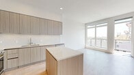 This modern 2-bedroom, 2-bathroom residence in San Diego's 92103 neighborhood offers a thoughtfully designed single-floor layout with clean, contemporary finishes throughout. Light wood-tone flooring flows seamlessly across the entire unit, creating a warm and cohesive aesthetic.

The open-concept kitchen and living area serves as the heart of the home. The kitchen is outfitted with flat-front, wood-grain cabinetry, quartz countertops, a marble-style tile backsplash, a central island, and a full suite of stainless steel appliances including a refrigerator, range, microwave, and dishwasher. Large floor-to-ceiling windows in the adjacent living area invite abundant natural light and provide open outdoor views.

The primary bedroom is a comfortable, well-proportioned space featuring direct access to a private balcony with city views. Its en-suite bathroom includes a wood-grain vanity with a white quartz countertop, a large frameless glass walk-in shower with stone tile surround, and access to a dedicated closet. The second bedroom is bright and airy, with a large window offering natural light and urban views, accompanied by a sliding-door closet with built-in shelving. A second full bathroom serves the remaining rooms. The overall ambiance is modern, minimalist, and move-in ready.