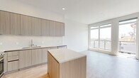 This modern 2-bedroom, 2-bathroom residence in San Diego's 92103 neighborhood offers a thoughtfully designed single-floor layout with clean, contemporary finishes throughout. Light wood-tone flooring flows seamlessly across the entire unit, creating a warm and cohesive aesthetic.

The open-concept kitchen and living area serves as the heart of the home. The kitchen is outfitted with flat-front, wood-grain cabinetry, quartz countertops, a marble-style tile backsplash, a central island, and a full suite of stainless steel appliances including a refrigerator, range, microwave, and dishwasher. Large floor-to-ceiling windows in the adjacent living area invite abundant natural light and provide open outdoor views.

The primary bedroom is a comfortable, well-proportioned space featuring direct access to a private balcony with city views. Its en-suite bathroom includes a wood-grain vanity with a white quartz countertop, a large frameless glass walk-in shower with stone tile surround, and access to a dedicated closet. The second bedroom is bright and airy, with a large window offering natural light and urban views, accompanied by a sliding-door closet with built-in shelving. A second full bathroom serves the remaining rooms. The overall ambiance is modern, minimalist, and move-in ready.