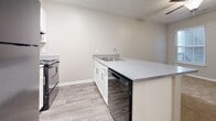 Located at 161 Lansing Cir in Mooresville, NC, this single-floor, one-bedroom, one-bathroom residence offers a thoughtfully organized layout that makes excellent use of its compact footprint. The kitchen is a functional centerpiece, featuring white shaker-style cabinetry, light stone-look countertops extending across a peninsula with a built-in sink, and black appliances including a refrigerator and range. Wood-look luxury vinyl plank flooring runs throughout the kitchen and main living areas, lending a clean, cohesive look. The bedroom is a comfortable, well-proportioned retreat finished with soft wall-to-wall carpeting, neutral taupe walls, a ceiling fan, and a window that invites natural light and views of surrounding greenery. The bathroom includes a full soaking tub with a clean white surround. A dedicated laundry room provides added convenience, equipped with washer and dryer connections, overhead wire shelving for storage, and durable hard-surface flooring. Throughout the residence, crisp white trim, neutral wall tones, and consistent finishes create a bright, move-in-ready atmosphere suited for efficient, comfortable everyday living.