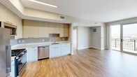 Located in Stamford, Connecticut, this two-bedroom, one-bathroom residence at Allure 1405 offers a well-designed, modern living environment with a cohesive aesthetic throughout. Warm hardwood-style flooring runs continuously across the open-concept layout, connecting the kitchen, living room, and bedrooms with a unified, contemporary feel. Neutral-toned walls and clean white trim complement the light-filled interiors.

The kitchen is a standout feature, equipped with stainless steel appliances including a gas range, over-the-range microwave, refrigerator, and dishwasher. Two-toned cabinetry—white lower cabinets paired with natural wood upper cabinets—frames a light stone countertop, offering both style and functionality. The kitchen flows seamlessly into the open living area, making the space feel expansive and connected.

Both bedrooms are generously proportioned, benefiting from floor-to-ceiling windows that invite abundant natural light and offer impressive elevated views of the surrounding Stamford cityscape. The primary bedroom features direct access to a private balcony through sliding glass doors, further enhancing the sense of openness.

The bathroom is finished with a marble-style quartz vanity countertop, a large mirror, modern fixtures, and a full tub-shower combination with tiled surround. Every detail reflects a clean, contemporary design sensibility ideal for modern urban living.