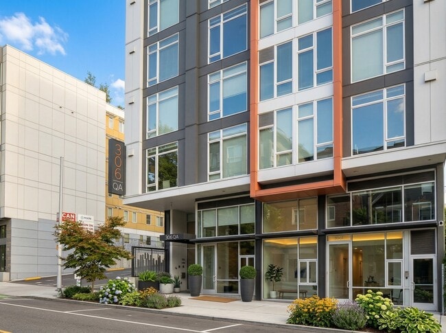 Street-level view of 306 Queen Anne in Seattle showing the main entrance, glass lobby frontage, and landscaped sidewalk planters. - 306 Queen Anne