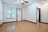 Located at 2585 University Ave in Madison, Wisconsin, this well-appointed unit offers a thoughtfully designed single-floor layout that maximizes functionality and comfort. The heart of the space is an open-concept kitchen and living area, where warm bamboo-style hardwood flooring flows seamlessly underfoot. The kitchen is highlighted by rich wood cabinetry, dark granite countertops, a central island with pendant lighting, and black appliances including a refrigerator, range, and microwave. A ceiling fan overhead and a welcoming entry door with sidelight windows add to the living area's bright and airy feel. The bedroom features plush carpeting, a ceiling fan, and a window framing views of the tree-lined neighborhood outside. Three closets provide generous storage throughout, including a well-organized walk-in closet with built-in shelving. The bathroom offers a clean, functional layout with wood-toned finishes consistent with the rest of the unit. An in-unit laundry area adds everyday convenience. Track lighting and pendant fixtures provide layered illumination throughout. A covered exterior entry overlooks a lush, green neighborhood streetscape, offering a pleasant sense of place within the Madison community.