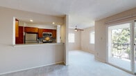 This single-floor residence offers a thoughtfully laid-out living space with a seamless connection between the kitchen and living room. The open-concept design features a peninsula-style kitchen equipped with warm-toned wood cabinetry, granite-style countertops, a tile backsplash, and stainless steel appliances including a refrigerator, microwave, and range. Tile flooring runs through the kitchen, providing a practical and clean surface. The adjacent living area is generously sized, finished with soft neutral carpeting and warmed by natural light streaming through multiple windows. A ceiling fan with a light fixture adds both comfort and functionality to the living space. A sliding glass door opens to a balcony, extending the living area outdoors and offering views of surrounding greenery. The bedrooms are well-proportioned, each carpeted and equipped with ceiling fans, with one featuring a sliding closet door. The bathroom is finished with tile flooring, warm wood cabinetry, a combined shower and bathtub, and chrome fixtures. Textured ceilings are consistent throughout, and neutral wall tones create a clean, adaptable canvas across all rooms. The overall layout is efficient and practical, providing comfortable single-level living.