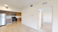 Located at 502 NW 207th St in Miami Gardens, Florida, this single-floor unit offers a clean, contemporary design characterized by a bright, neutral palette and light-toned tile flooring throughout. The open-concept living and dining area is generously proportioned, bathed in natural light, and anchored by sliding glass doors that open to a private balcony overlooking lush outdoor greenery — an ideal setting for relaxing or entertaining.

The kitchen is efficiently designed with warm wood-toned cabinetry, white quartz countertops, a stainless steel undermount sink, and a full suite of stainless steel appliances, including a refrigerator, electric range, built-in microwave, and dishwasher. Ample upper and lower cabinet storage enhances everyday functionality.

The bedroom is a quiet, well-lit space featuring a window with outdoor views and a louvered closet door providing dedicated storage. The bathroom is notably spacious, featuring an elongated dual-sink vanity with wood cabinetry and white countertops, large wall mirrors with overhead lighting, large-format tile flooring, and a separate toilet and walk-in shower area. The overall ambiance of the unit is fresh, modern, and move-in ready.