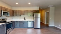 This thoughtfully designed single-floor residence offers a seamless blend of modern style and functional living. The kitchen serves as a standout feature, showcasing rich two-toned cabinetry with dark lower cabinets and warm wood-toned uppers, crisp white countertops, and a full suite of stainless steel appliances including a refrigerator, dishwasher, electric range, and microwave. Recessed lighting illuminates the space, which flows easily into adjacent living areas with warm-toned walls and durable wood-style flooring throughout.

The bedrooms are bright and inviting, benefiting from large windows that frame views of surrounding greenery. One bedroom features soft carpeting, adding warmth and comfort underfoot, while the light-filled rooms provide a calm, airy atmosphere.

The bathrooms are finished with care and attention to detail. One features a sleek LED-backlit mirror, a wood-toned vanity with white countertop, matte black fixtures, and a tiled tub-and-shower combo. A second bathroom offers a clean vanity setup with coordinating finishes. Throughout the home, crisp white trim, panel-style doors with matte black hardware, and consistent wood-look flooring tie each space together in a cohesive, contemporary aesthetic.