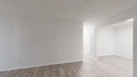 Located at 1075 N Hairston Rd in Stone Mountain, GA, this one-bedroom, one-bathroom unit offers a clean, modern aesthetic across a well-organized single-floor layout. Light wood-look flooring runs throughout the entire space, complementing the crisp white walls and creating a bright, cohesive feel.

The living room provides a comfortable and open area anchored by a large sliding glass door with vertical blinds, allowing natural light to fill the room. Adjacent to the living area, the galley-style kitchen is efficiently designed with ample white cabinetry featuring black hardware, a marble-style countertop, a single-basin sink with a matte black faucet, and full appliances including a refrigerator and range. A dedicated overhead light keeps the kitchen bright and functional.

The bedroom is a generously sized room with a window overlooking greenery outdoors, offering natural light and outdoor views. Textured ceilings add subtle character to the space. The bedroom connects to a dedicated walk-in closet outfitted with dual-level shelving rods on both sides, providing substantial storage capacity.

The bathroom features a white vanity with a clean countertop, a wall-mounted mirror, and a separate wet area housing a full tub and shower combination with a curtain rod. Light flooring continues here, maintaining the consistent aesthetic throughout the unit.