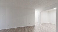 Located at 1075 N Hairston Rd in Stone Mountain, GA, this one-bedroom, one-bathroom unit offers a clean, modern aesthetic across a well-organized single-floor layout. Light wood-look flooring runs throughout the entire space, complementing the crisp white walls and creating a bright, cohesive feel.

The living room provides a comfortable and open area anchored by a large sliding glass door with vertical blinds, allowing natural light to fill the room. Adjacent to the living area, the galley-style kitchen is efficiently designed with ample white cabinetry featuring black hardware, a marble-style countertop, a single-basin sink with a matte black faucet, and full appliances including a refrigerator and range. A dedicated overhead light keeps the kitchen bright and functional.

The bedroom is a generously sized room with a window overlooking greenery outdoors, offering natural light and outdoor views. Textured ceilings add subtle character to the space. The bedroom connects to a dedicated walk-in closet outfitted with dual-level shelving rods on both sides, providing substantial storage capacity.

The bathroom features a white vanity with a clean countertop, a wall-mounted mirror, and a separate wet area housing a full tub and shower combination with a curtain rod. Light flooring continues here, maintaining the consistent aesthetic throughout the unit.