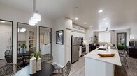 This single-floor residence offers a thoughtfully designed open-concept layout that seamlessly connects the kitchen, dining, and living areas. The kitchen is a standout feature, showcasing white shaker cabinetry, stainless steel appliances including a refrigerator, gas range, and built-in microwave, and a generous island with quartz countertops and bar seating for multiple guests. Recessed lighting illuminates the space, while wood-look plank flooring flows throughout the main living areas.

The dining area is positioned near a glass block window that filters in natural light, and is anchored by a contemporary pendant chandelier. The living room is bright and airy, featuring a ceiling fan, large windows with draping curtains, and ample space for comfortable seating arrangements.

The bedroom is a serene retreat with plush carpeting, a ceiling fan, and sliding glass doors opening to a private outdoor patio. A dedicated laundry room provides side-by-side washer and dryer units for added convenience. The bathroom is well-equipped with a tub-shower combination, a vanity with quartz countertops, white cabinetry, and wood-look tile flooring. Throughout, the neutral color palette and modern finishes create a cohesive and inviting atmosphere.