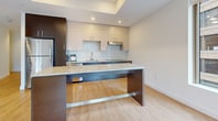 This contemporary 900 square foot apartment in downtown Boston offers a blend of style and functionality. The open-concept living area is highlighted by tray ceilings, recessed lighting, and large windows that frame stunning city views. The sleek kitchen boasts modern cabinetry, a granite-topped island, and stainless steel appliances. Both bedrooms are generously sized, with the primary bedroom measuring 150 square feet. The two bathrooms feature modern fixtures, including a walk-in shower with a curved rod in one and a bathtub in the other. Wood-look flooring runs throughout the apartment, creating a warm, cohesive aesthetic. The space is further enhanced by two closets for ample storage. Located at 1 Greenway Street, this 10th-floor apartment (APT:1001) puts residents in the heart of Boston's vibrant urban landscape, offering a perfect blend of comfort and city living.