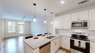 Located in Huntersville, NC, this thoughtfully designed 1-bedroom, 1-bathroom residence offers a clean, modern aesthetic throughout its single-floor layout. Warm hardwood flooring flows seamlessly through every room, complementing the bright, neutral color palette that gives the entire space an open and airy feel.

The kitchen is a standout feature, outfitted with crisp white cabinetry, granite countertops, a tile backsplash, and a full suite of stainless steel appliances including a refrigerator, electric range, and built-in microwave. A pendant-lit island provides additional prep space and casual seating.

The living area is bathed in natural light through large windows and a glass door that opens onto a private balcony, offering picturesque views of the community pool and landscaped grounds. A ceiling fan adds comfort to both the living area and the generously sized bedroom, which also benefits from multiple windows framing neighborhood views.

The bedroom connects to a well-organized walk-in closet with wire shelving. The full bathroom features a tub-shower combination, granite vanity countertop, and hardwood flooring, maintaining the polished look found throughout the home. A dedicated hallway provides clear separation between the living and sleeping areas, enhancing the overall functionality of the layout.