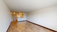 Located at 110 SE Washington Street in Hillsboro, Oregon, this one-bedroom, one-bathroom unit offers a practical and well-organized single-floor layout. The combined living and dining area is the heart of the home, featuring wood-style laminate flooring, neutral white walls, a ceiling fan, and a window that fills the space with natural light and outdoor views. The galley-style kitchen is efficiently designed with white cabinetry trimmed in warm wood tones, laminate countertops, a stainless steel sink, and white appliances including a range and refrigerator. A breakfast bar separates the kitchen from the living area, enhancing the open feel. The bedroom is a comfortable retreat finished with plush carpeting, a large window with blinds offering neighborhood views, and a dedicated closet. A second closet provides additional storage. The full bathroom includes a combination tub and shower, toilet, and a vanity with a countertop sink, all finished with wood-style flooring. An in-unit laundry area and a dedicated entrance add everyday convenience. Throughout the unit, a clean, neutral palette and consistent finishes create a cohesive and functional living environment.