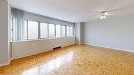 This well-appointed one-bedroom, one-bathroom unit in Toronto offers a thoughtfully laid-out single-floor plan with generous overall living space. Warm parquet hardwood flooring flows consistently throughout the living areas, hallway, and bedroom, lending the home a cohesive and inviting character.

The spacious living room is a standout feature, boasting a full wall of large, floor-to-ceiling windows that fill the room with abundant natural light and offer elevated views of the surrounding Toronto cityscape. A ceiling fan adds to the room's comfort and functionality.

The kitchen is efficiently designed with ample white cabinetry, both upper and lower, complemented by neutral countertops and light ceramic tile flooring. It is equipped with a full-size refrigerator, dishwasher, and a double sink, providing practical functionality.

The generously sized primary bedroom features the same warm parquet flooring and includes access to a dedicated closet with built-in hanging rods, offering strong storage capacity. A secondary door from the bedroom provides convenient connectivity to the rest of the unit.

The bathroom is clean and functional, featuring light tile flooring, a wood-toned vanity with a large mirror, and a full tub-shower combination with tile surround. A hallway with a dedicated closet completes the layout, adding further storage to this well-organized Toronto residence.