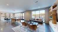 Located at 394 West Ave in Norwalk, CT, this thoughtfully designed single-floor space blends modern aesthetics with functional living. Polished concrete floors run throughout, lending an industrial-chic character that ties each area together seamlessly.

The welcoming entrance features a sleek, minimalist design with a bold round mirror, a dark console table, and glass-paneled partitions that set a contemporary tone from the moment you arrive. A connecting hallway guides visitors deeper into the space with clean lines and recessed lighting overhead.

The combined dining and living area is the heart of the space, offering an open, airy layout bathed in abundant natural light. Floor-to-ceiling black-framed windows provide sweeping views of the outdoor terrace and surrounding Norwalk cityscape, creating a seamless connection between interior and exterior. The living zone features built-in natural pine shelving for both storage and display, while the dining area accommodates a generous long table ideal for group gatherings.

Along one wall, a well-appointed kitchenette showcases light pine cabinetry, dark stone countertops, and a stylish tiled backsplash — a refined yet practical feature. Recessed lighting throughout ensures a bright, inviting ambiance, while the neutral palette of warm whites and natural wood tones creates a calm, sophisticated atmosphere throughout.