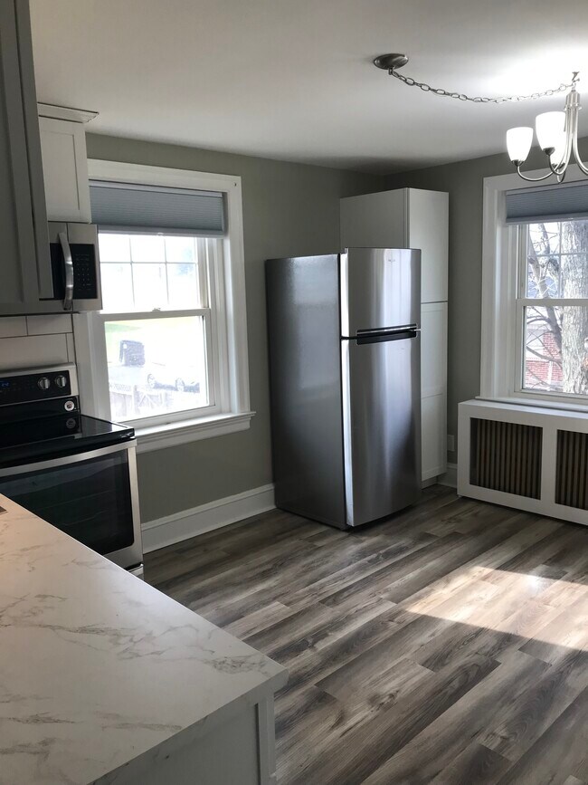 Cocina recién reformada con armarios blancos, salpicadero de azulejos tipo metro y electrodomésticos de acero inoxidable. - 430 Main St