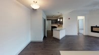 This two-story residence is thoughtfully designed with a clean, modern aesthetic throughout. The kitchen serves as a focal point on the main level, showcasing rich dark cabinetry, granite countertops with a subtle veining pattern, a tile backsplash, and black appliances including an electric range and built-in microwave. A central island with a white base and matching granite surface provides additional prep space and opens to the living area, which features dark hardwood-style flooring and a ceiling fan for comfort. A dedicated laundry closet on the main level adds practical convenience.

Upstairs, the bedrooms are finished with plush carpeting and ceiling fans, lending a comfortable and quiet retreat. The primary bedroom includes access to a walk-in closet, offering generous storage. A second bedroom also benefits from natural light through a window overlooking the surrounding neighborhood. The bathroom is well-appointed with a soaking tub and shower combination, accented by large-format gray tile surround, dark wood-style flooring, and brushed nickel hardware and grab bars.

Completing the layout is an attached garage with an automatic opener, providing secure and convenient parking or additional storage space.