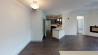 This two-story residence is thoughtfully designed with a clean, modern aesthetic throughout. The kitchen serves as a focal point on the main level, showcasing rich dark cabinetry, granite countertops with a subtle veining pattern, a tile backsplash, and black appliances including an electric range and built-in microwave. A central island with a white base and matching granite surface provides additional prep space and opens to the living area, which features dark hardwood-style flooring and a ceiling fan for comfort. A dedicated laundry closet on the main level adds practical convenience.

Upstairs, the bedrooms are finished with plush carpeting and ceiling fans, lending a comfortable and quiet retreat. The primary bedroom includes access to a walk-in closet, offering generous storage. A second bedroom also benefits from natural light through a window overlooking the surrounding neighborhood. The bathroom is well-appointed with a soaking tub and shower combination, accented by large-format gray tile surround, dark wood-style flooring, and brushed nickel hardware and grab bars.

Completing the layout is an attached garage with an automatic opener, providing secure and convenient parking or additional storage space.