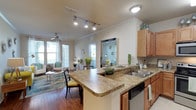 This single-floor residence offers a thoughtfully designed layout that balances comfort and functionality. The open-concept kitchen flows seamlessly into the dining and living areas, creating an inviting, connected space. The kitchen is equipped with stainless steel appliances, including a gas range and built-in microwave, warm wood cabinetry, granite-style countertops, and a peninsula with bar seating. Rich hardwood-style flooring runs throughout the main living area, which features crown molding, a ceiling fan, and large windows with a glass door that invite generous natural light and outdoor views.

The primary bedroom is a serene retreat highlighted by a bold teal accent wall, plush carpeting, and a window that brightens the room. It connects to a full bathroom with a dual-sink vanity, granite countertops, wood cabinetry, and a tub-shower combination. The second bedroom features a vibrant olive green accent wall, large windows, and soft carpet underfoot, accompanied by its own full bathroom with similar finishes.

A dedicated kitchen area also includes tile flooring and ample cabinetry for storage. The residence additionally includes a utility area housing a water heater. Throughout the space, crown molding, ceiling fans, and a cohesive neutral palette with colorful accents contribute to a polished, livable ambiance.