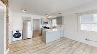 Located at 435 E 100 S in Salt Lake City, this one-bedroom, one-bathroom unit offers a thoughtfully updated interior that balances historic character with contemporary finishes. Light oak-toned luxury vinyl plank flooring runs throughout the entire space, creating a cohesive and clean aesthetic.

The kitchen serves as a central highlight, featuring gray shaker-style cabinetry, white subway tile backsplash, light quartz countertops, and a peninsula that provides additional workspace. Stainless steel appliances — including a full-size refrigerator, range, and microwave — are fully integrated. A standout architectural detail is the exposed brick wall near the entry, which adds warmth and industrial character to the otherwise modern interior.

The bedroom is a compact, efficiently proportioned room with white walls, a window fitted with blinds that allows natural light in, and consistent flooring throughout. The bathroom features floor-to-ceiling white subway tile, a compact gray vanity with a gold-toned faucet, a round black-framed mirror, and a bathtub, presenting a clean, minimal aesthetic. The unit's single-floor layout maximizes usability within its modest footprint.