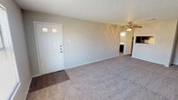 This single-floor, one-bedroom, one-bathroom unit offers a functional and straightforward layout designed for comfortable everyday living. The living area is generously proportioned, featuring neutral-toned carpet, light gray walls, a textured ceiling, and a ceiling fan with an integrated light fixture. A front entry door with decorative glass inserts opens directly into this space, which also benefits from a window allowing natural light to filter in. A pass-through window connects the living area to the kitchen, enhancing the open feel between the two spaces.

The galley-style kitchen is efficiently arranged, featuring dark espresso cabinetry on both sides, light-toned countertops, a double stainless steel sink, and a black electric coil range with overhead ventilation. Wood-look flooring runs throughout the kitchen, adding a warm contrast to the darker cabinetry.

The bedroom is a comfortable size, finished with carpet, a ceiling fan with lighting, a window with exterior views, and neutral walls throughout. The full bathroom includes wood-look flooring, a dark vanity with a light countertop, a standard toilet, and a tub-shower combination with tiled surround, offering clean and practical finishes.